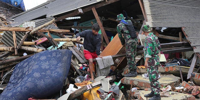 Indonesian soldiers and people clean up the debris following the tsunami in Sumur, Indonesia, on Tuesday.