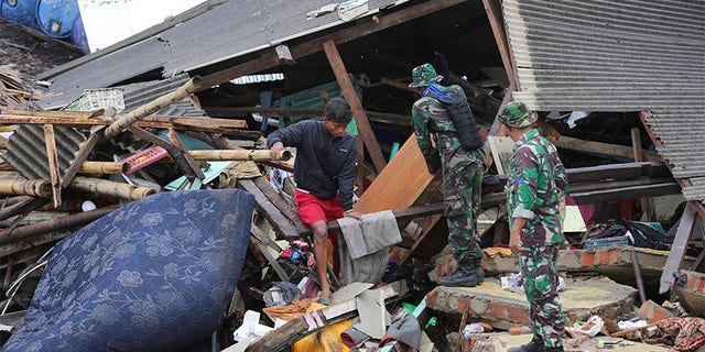 Indonesian soldiers and people clean up the debris following the tsunami in Sumur, Indonesia, on Tuesday.
