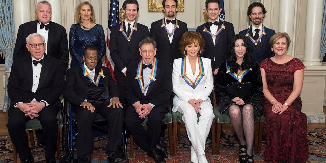 Front row from left, David Rubenstein, 2018 Kennedy Center Honorees Wayne Shorter, Philip Glass, Reba McEntire, Cher, Kennedy Center President Deborah Rutter; back row from left, Deputy Secretary of State John Sullivan, Grace Rodriguez, and the 2018 Kennedy Center Honorees, the co-creators of "Hamilton," Thomas Kail, Lin-Manuel Miranda, Andy Blankenbuehler, and Alex Lacamoire pose for the group photo at the State Department following the Kennedy Center Honors State Department Dinner on Saturday, Dec. 1, 2018, in Washington.