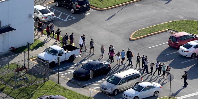 Students are evacuated by police from Marjory Stoneman Douglas High School in Parkland, Florida, Feb. 14, 2018, after a mass shooting that left 17 dead.