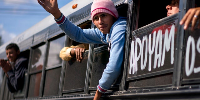 A migrant greets people while being transferred via a bus to a new shelter in Tijuana, Mexico, Saturday, Dec. 1, 2018. (AP Photo/Ramon Espinosa)