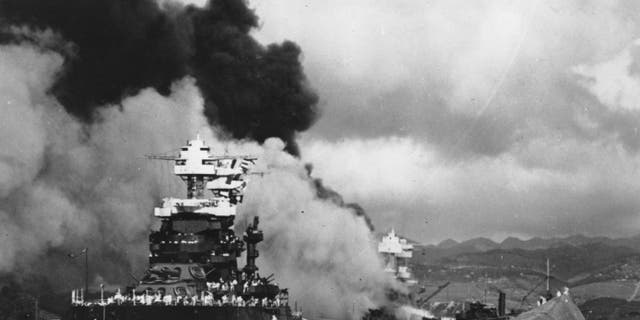 In this Dec. 7, 1941 file photo, part of the hull of the capsized USS Oklahoma is seen at right as the battleship USS West Virginia, center, begins to sink after suffering heavy damage, while the USS Maryland, left, is still afloat in Pearl Harbor, Oahu, Hawaii.