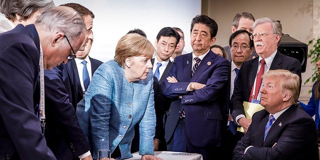 In this photo made available by the German Federal Government, German Chancellor Angela Merkel, center, speaks with U.S. President Donald Trump, seated at right, during the G7 Leaders Summit in La Malbaie, Quebec, Canada.