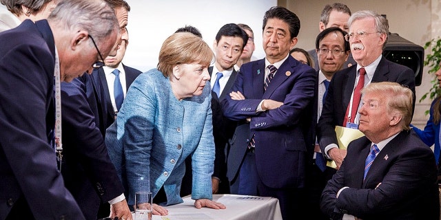 In this photo made available by the German Federal Government, German Chancellor Angela Merkel, center, talks to US President Donald Trump, seated right, during the G7 Leaders' Summit in La Malbaie, Quebec, Canada.