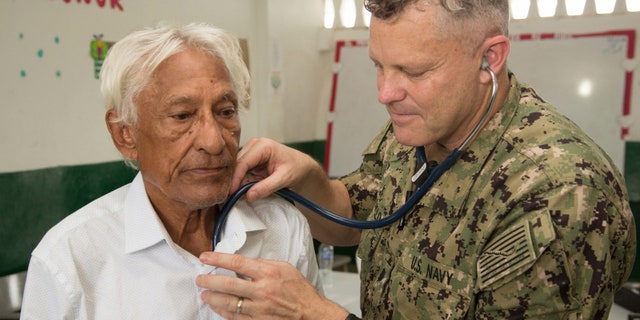 Cmdr. Ryan Griswold, from Madison, Iowa, examines a patient for health issues at one of two medical sites.