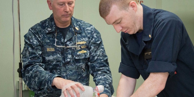 U.S. Navy Capt. Kevin Buss (left), director, nursing services, and Lt. Joseph Crossman, a midwife from Chesapeake, Va., participate in an advanced cardiac life support certification course in the intensive care unit aboard the hospital ship USNS Comfort (T-AH 20).