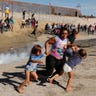 A migrant family, part of a caravan of thousands traveling from Central America en route to the United States, run from tear gas in front of the border wall between the U.S. and Mexico in Tijuana, Mexico November 25, 2018. 