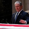 Former President George W. Bush touches the casket of his father, former President George H.W. Bush, at the State Funeral in Washington, Dec. 5, 2018.