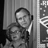 In this March 4, 1980 file photo, George H.W. Bush and an unidentified woman peek around a partition with a poster of Ronald Reagan, one of his opponents for the Republican party presidential nomination, before he speaks in Columbia, S.C.