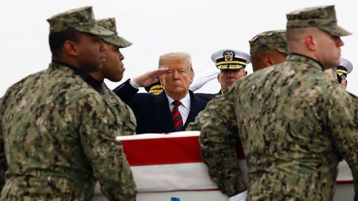 President Donald Trump salutes as a U.S. Navy carry team moves a transfer case containing the remains of Scott A. Wirtz, Saturday, Jan. 19, 2019, at Dover Air Force Base, Del. (AP Photo/Patrick Semansky)