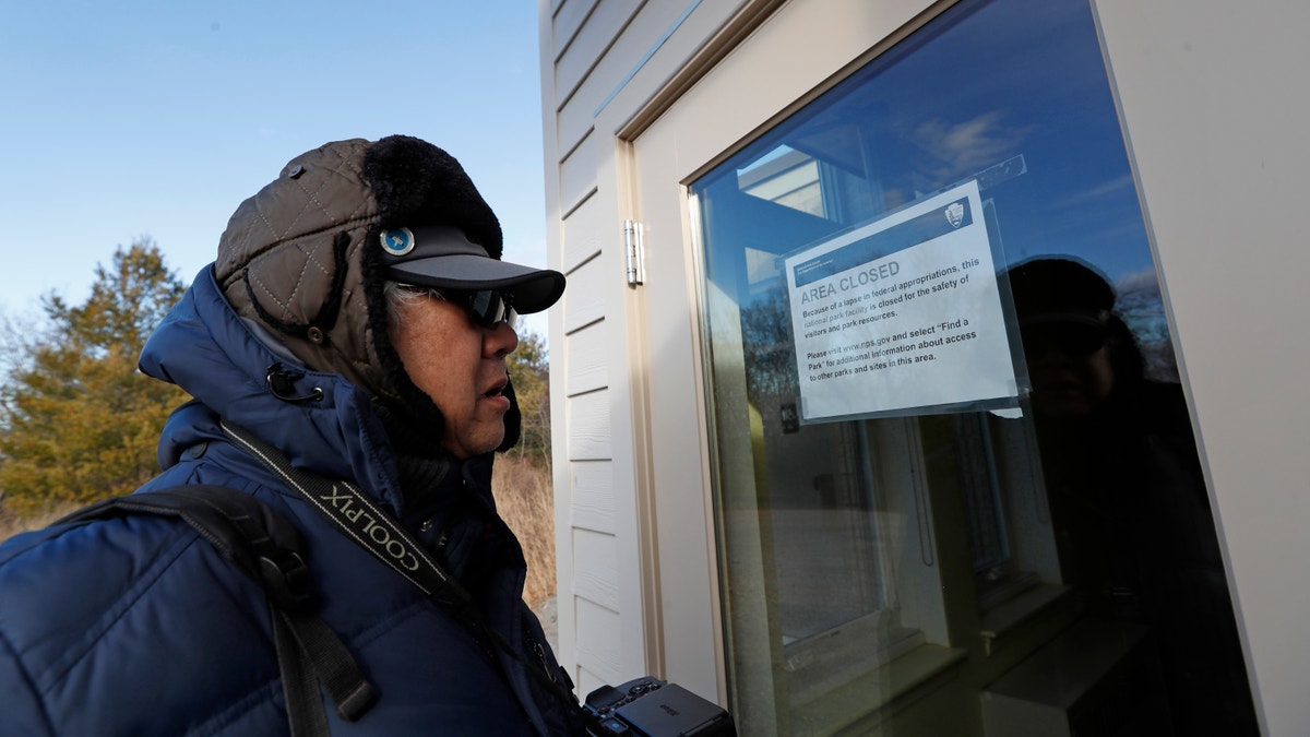 A New York resident is seen reading a notification announcing the temporary closure of a visitor's center at a Wildlife Refuge in Queens, N.Y., on Jan. 3.