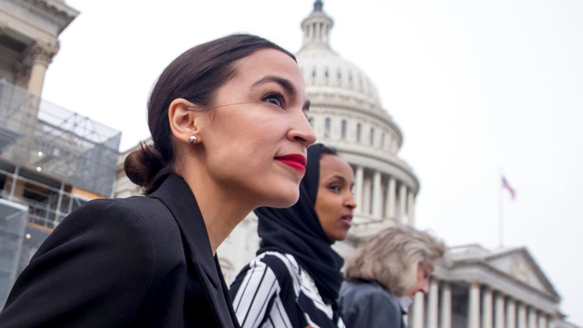 Rep. Alexandria Ocasio-Cortez, left, and D-N.Y., Rep. Ilhan Omar, D-Minn., center, walk down the House steps.