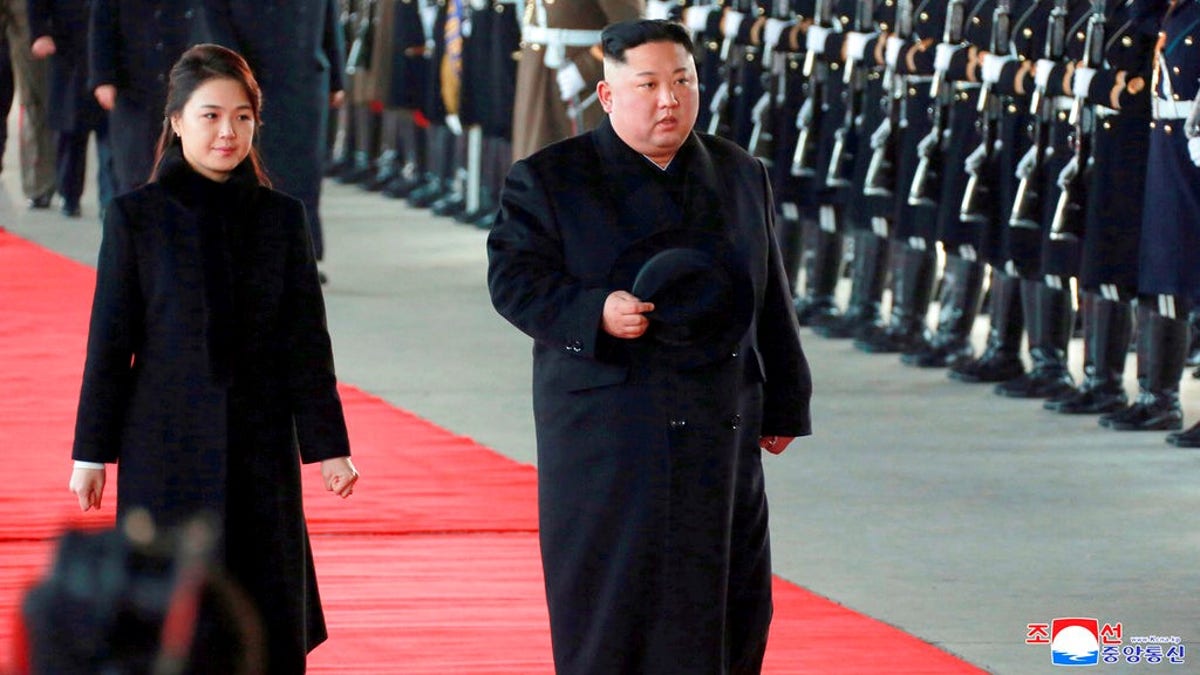 North Korean leader Kim Jong Un walks with his wife Ri Sol Ju at Pyongyang Station in Pyongyang, North Korea, before leaving for China.