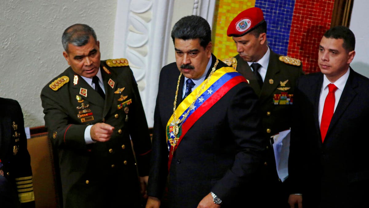 Venezuela's President Nicolas Maduro, center, stands with his Defense Minister Vladimir Padrino Lopez before giving his annual address to the nation to members of the Constitutional Assembly inside the National Assembly in Caracas, Venezuela, Monday, Jan. 14, 2019.