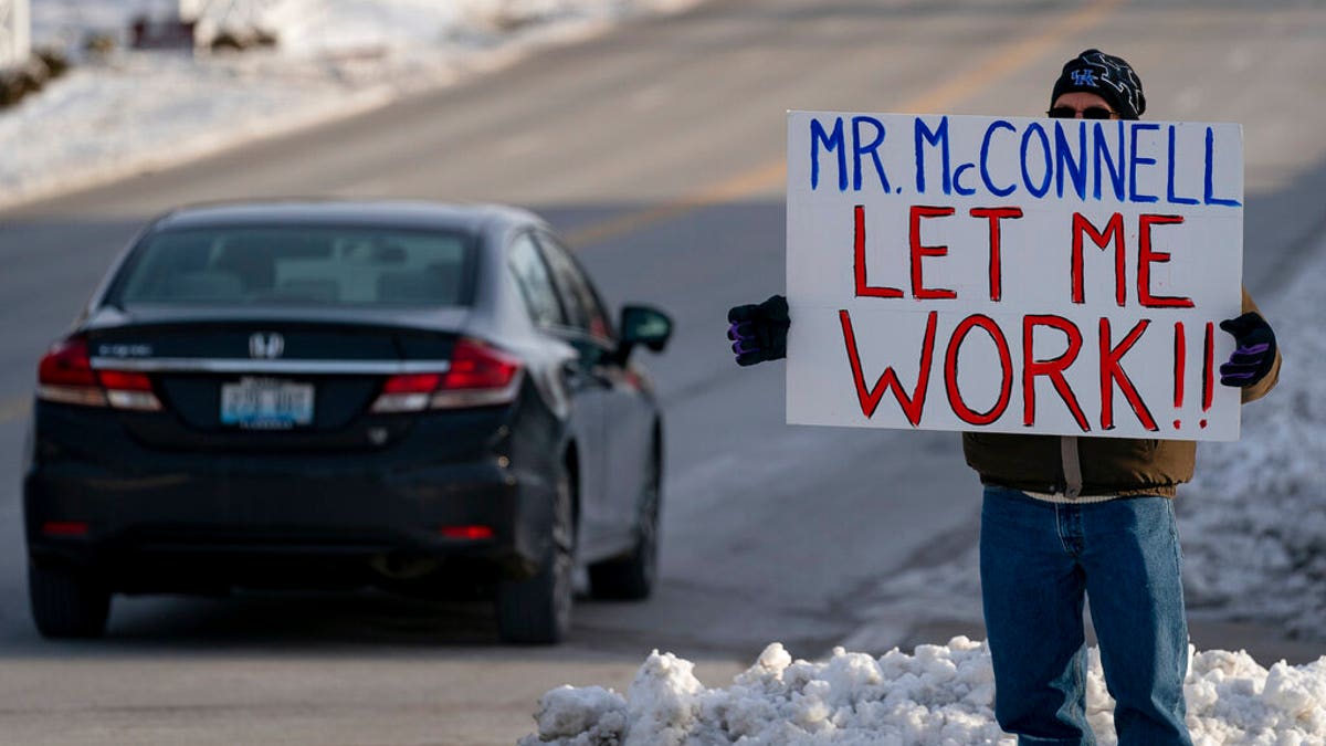 Furloughed EPA worker Jeff Herrema holds a sign outside the offices of U.S. Senator Mitch McConnell, in Park Hills, Ky., Tuesday, Jan 22, 2019. (AP Photo/Bryan Woolston)