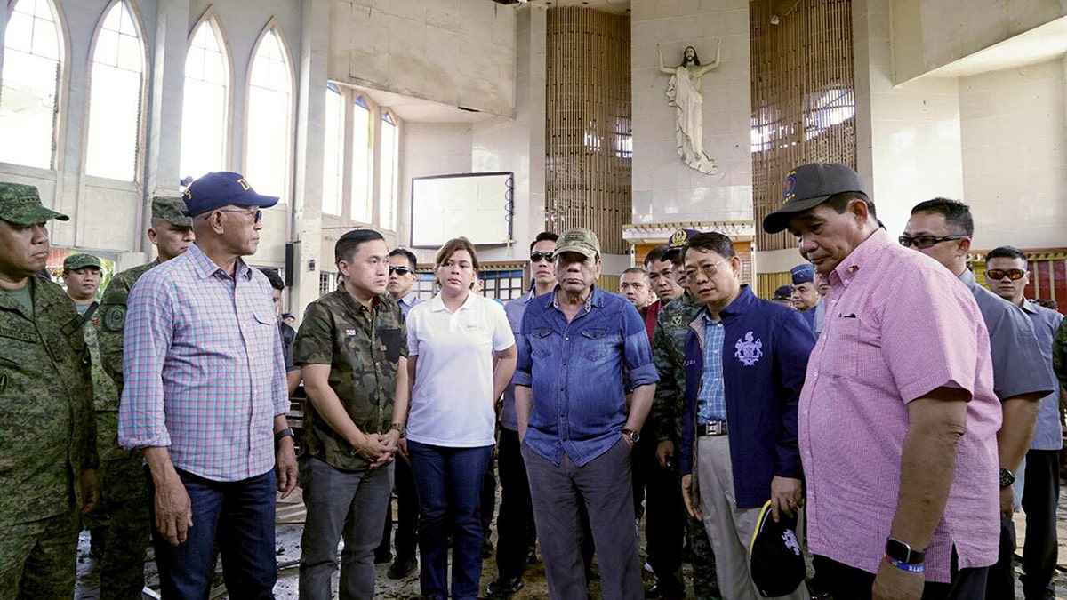 In this photo provided by Malacanang Palace, Philippine President Rodrigo Duterte, center wearing a cap, inspects a Roman Catholic Cathedral on Jolo, Sulu province in southern Philippines, Monday, Jan. 28, 2019, a day after two bombs exploded during a Sunday Mass. (Malacanang Palace Via AP)