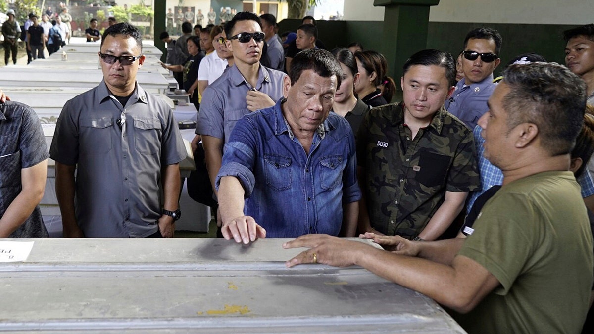In this photo provided by Malacanang Palace, Philippine President Rodrigo Duterte, center, touches one of the caskets of victims of Sunday's bombings of a Roman Catholic Cathedral on Jolo, Sulu province in southern Philippines, during his visit Monday, Jan. 28, 2019. The attack occurred in the Sulu provincial capital on Jolo island, where Abu Sayyaf militants have carried out years of bombings, kidnappings and beheadings and have aligned themselves with the Islamic State group, which claimed responsibility for the attack.(Malacanang Palace Via AP)
