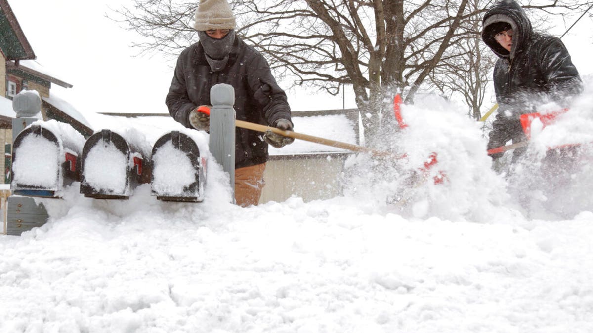 Residents clear a path to a series of mailboxes outside a multi-family home in Kewaskum, Wis. 