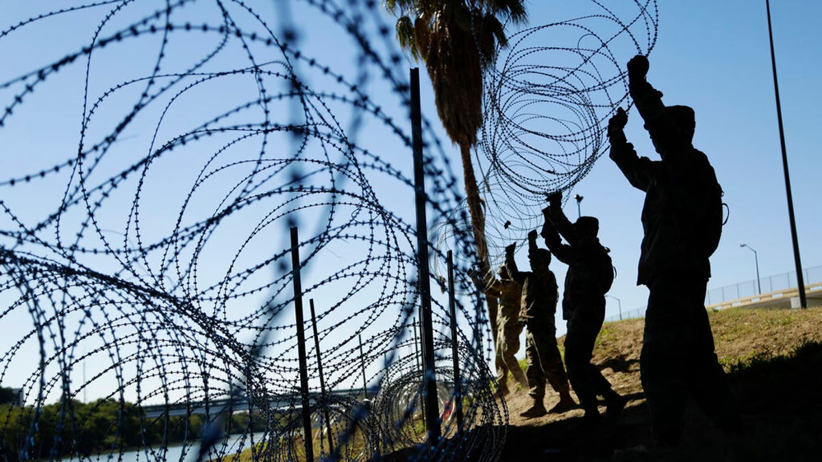 In this Nov. 16, 2018, file photo, members of the U.S. military install multiple tiers of concertina wire along the banks of the Rio Grande near the Juarez-Lincoln Bridge at the U.S.-Mexico border in Laredo, Texas.  (AP Photo/Eric Gay, File)