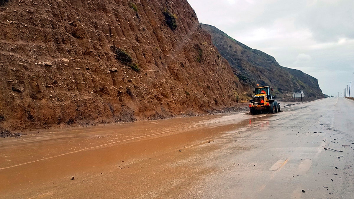 This photo provided by the California Department of Transportation (CalTrans) shows a skiploader clearing a river of mud that has flowed onto Pacific Coast Highway in Malibu, Calif., Monday, Jan. 14, 2019.