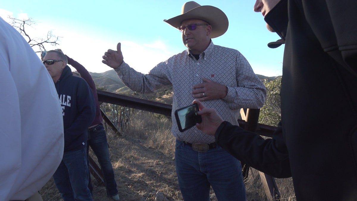 A rancher shows the congressmen and their staff a part of his ranch on the border where sticks, steel, and barbed wire separate his ranch from Mexico.