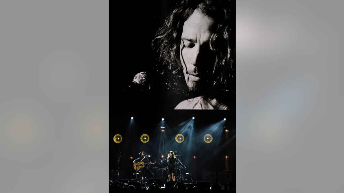 Toni Cornell, daughter of the late singer Chris Cornell, performs with Ziggy Marley, bottom left, underneath a video image of her father during "I Am The Highway: A Tribute to Chris Cornell"