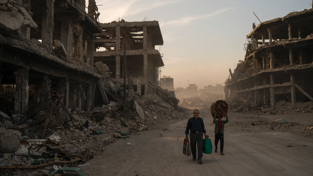 In this Nov. 15, 2017 file photo, Haider, left, and Abdullah carry belongings they collected from their damaged house to wash before returning to live in the Old City of Mosul, Iraq. (AP Photo/Felipe Dana)