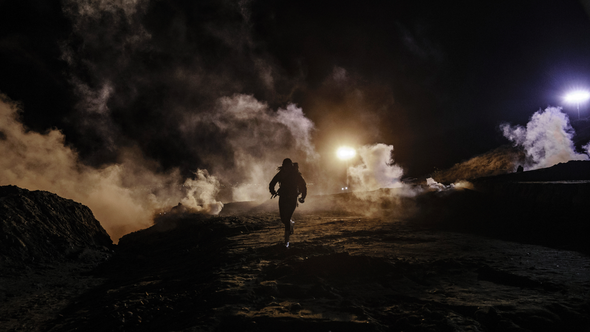 Migrants run as tear gas is thrown by U.S. Border Protection officers to the Mexican side of the border fence after they climbed the fence to get to San Diego, Calif., from Tijuana, Mexico, Tuesday, Jan. 1, 2019. Discouraged by the long wait to apply for asylum through official ports of entry, many migrants from recent caravans are choosing to cross the U.S. border wall and hand themselves in to border patrol agents. (AP Photo/Daniel Ochoa de Olza)