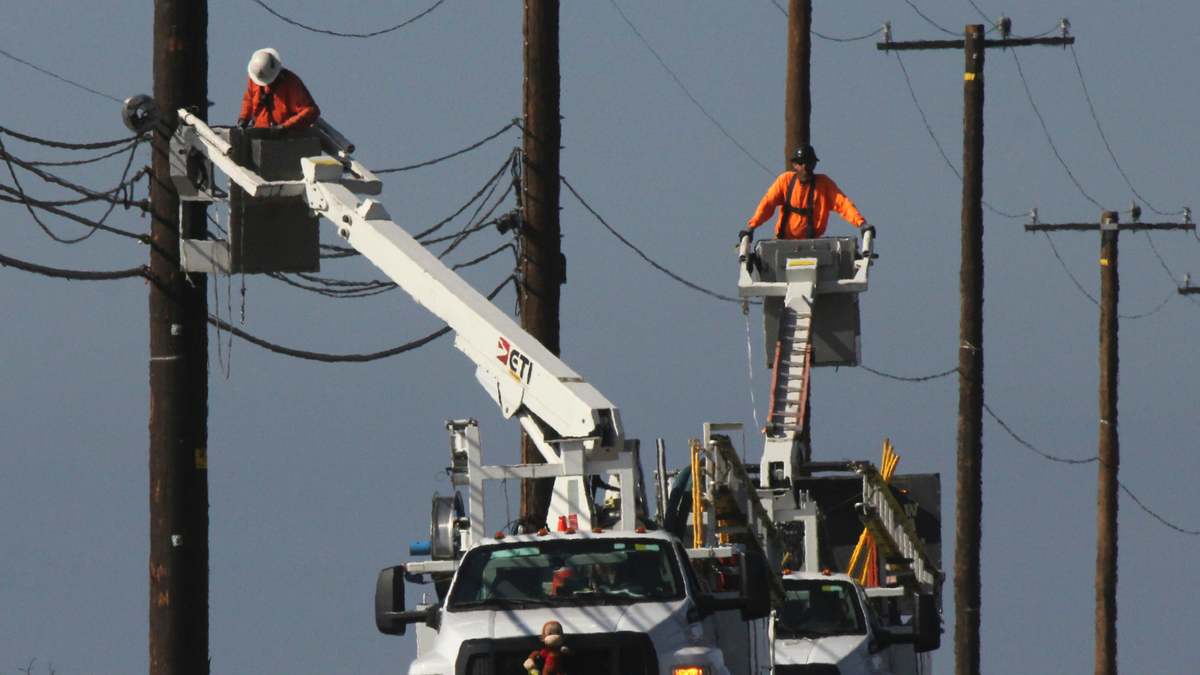 FILE - In this Sunday, Nov. 25, 2018 file photo, utility crews repair overhead lines along the Pacific Coast Highway just west of Malibu, Calif., where the Woolsey Fire burned down from the Santa Monica Mountains to the water's edge at Leo Carrillo State Beach. (AP Photo/John Antczak, File)