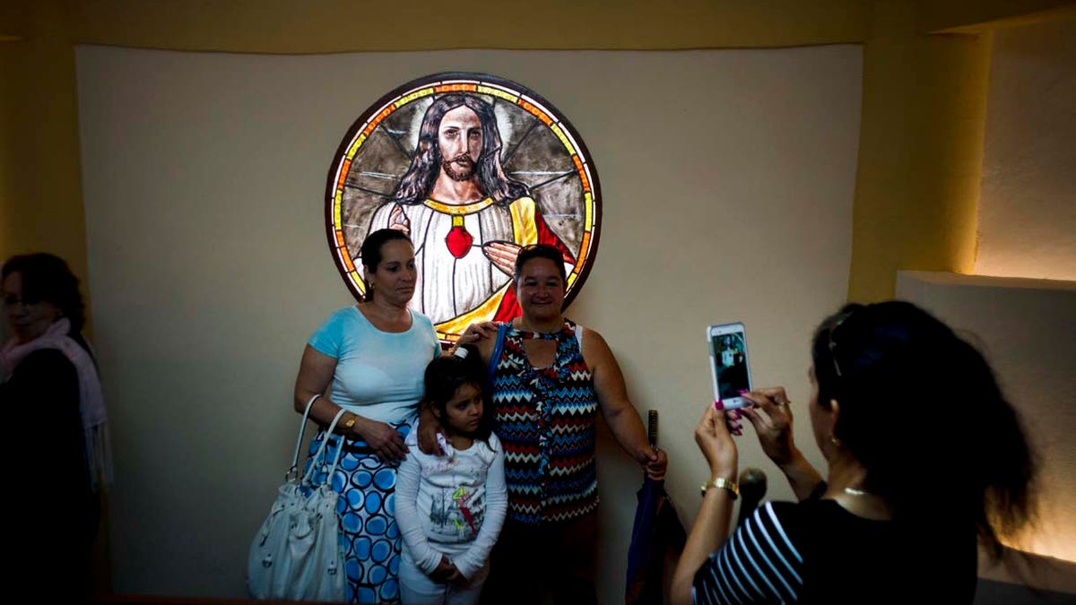 Parishioners pose for a photo backdropped by a stained glass window inside the newly consecrated Sagrado Corazon de Jesus Catholic church or Sacred Heart, in Sandino, Cuba, Saturday, Jan. 26, 2019. (AP Photo/Ramon Espinosa)