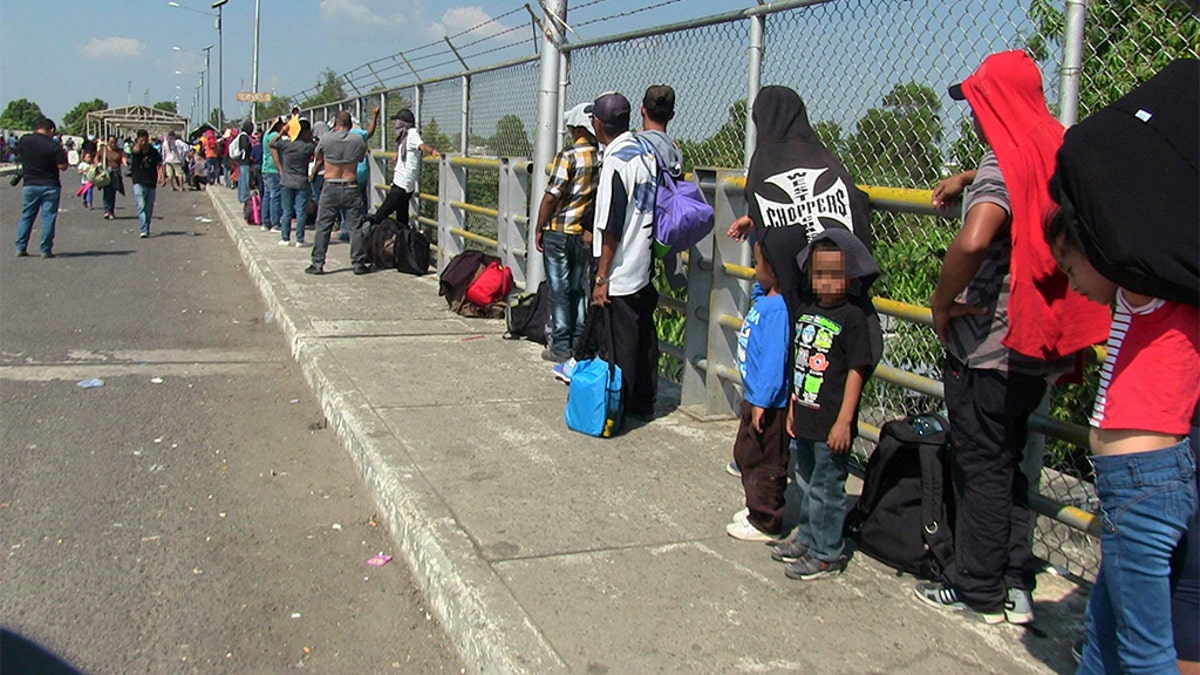 Around 300 migrants wait on the international bridge which divides Mexico and Guatemala. (GDA via AP Images)