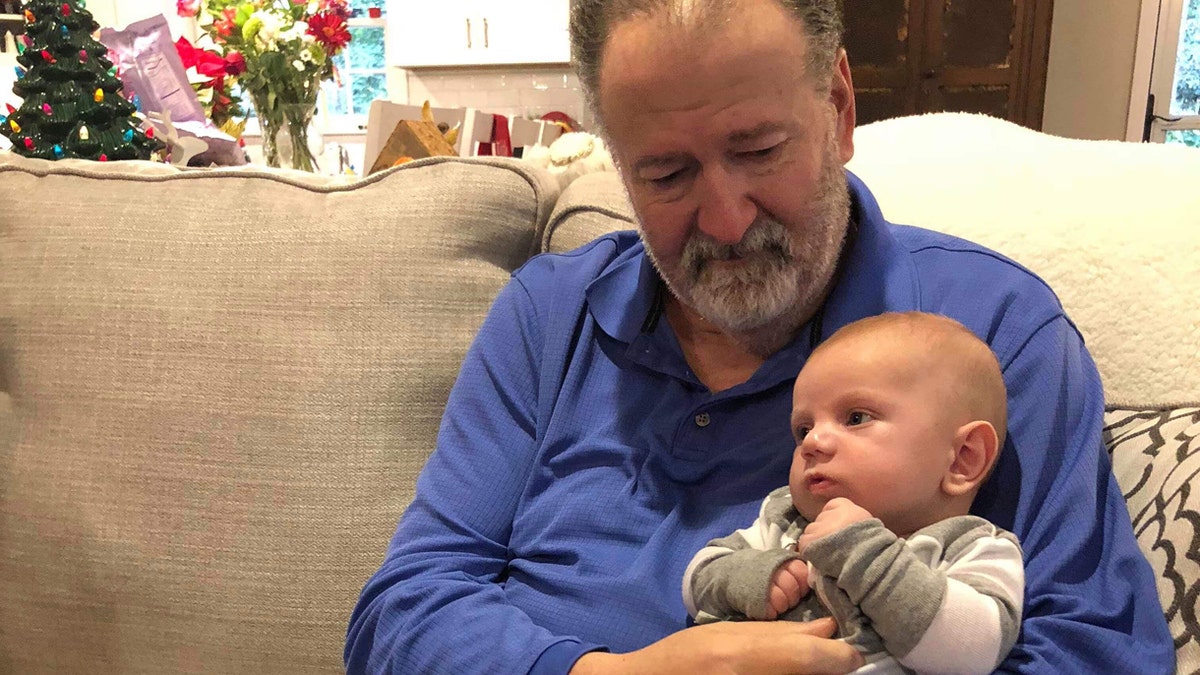 Mike Hodgin holds his grandson, Whitaker, after surviving a heart attack on Christmas Eve.