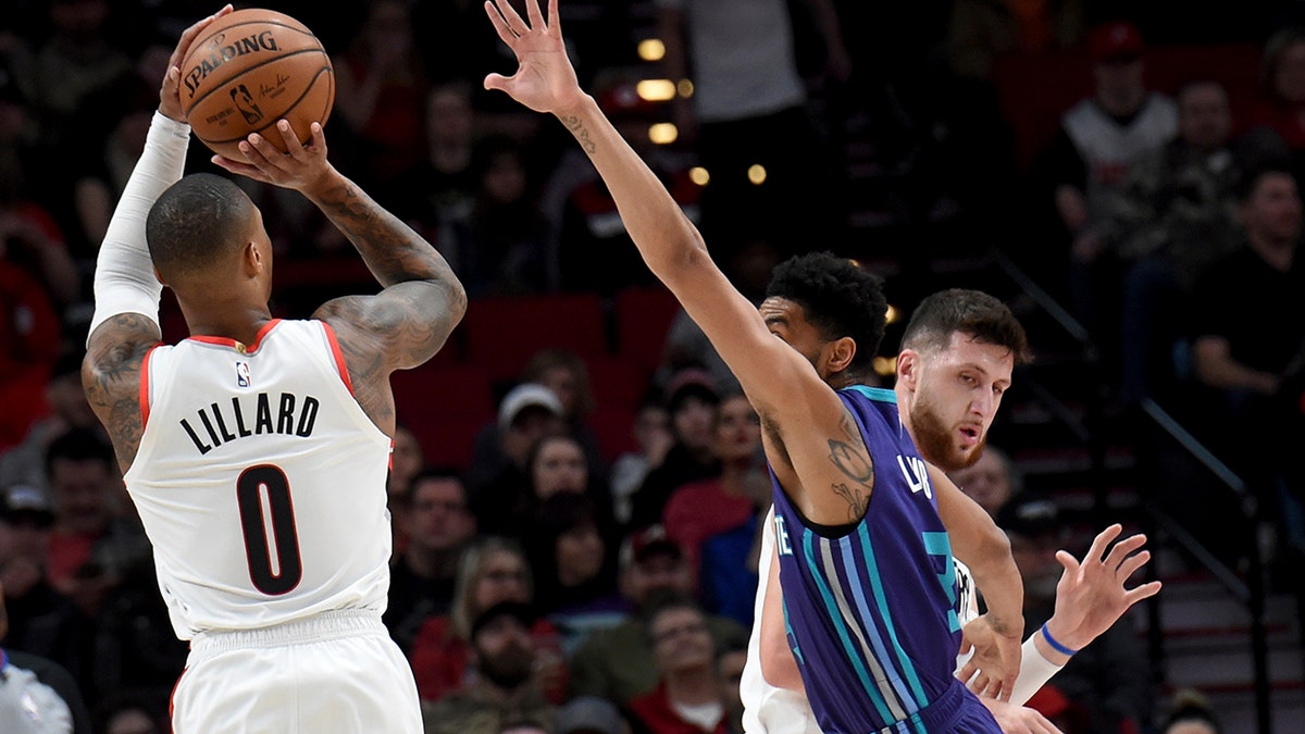 Portland Trail Blazers guard Damian Lillard, left, shoots a basket over Charlotte Hornets guard Jeremy Lamb, center, as center Jusuf Nurkic, right, sets a pick during the first half of an NBA basketball game in Portland, Ore., Friday, Jan. 11, 2019.