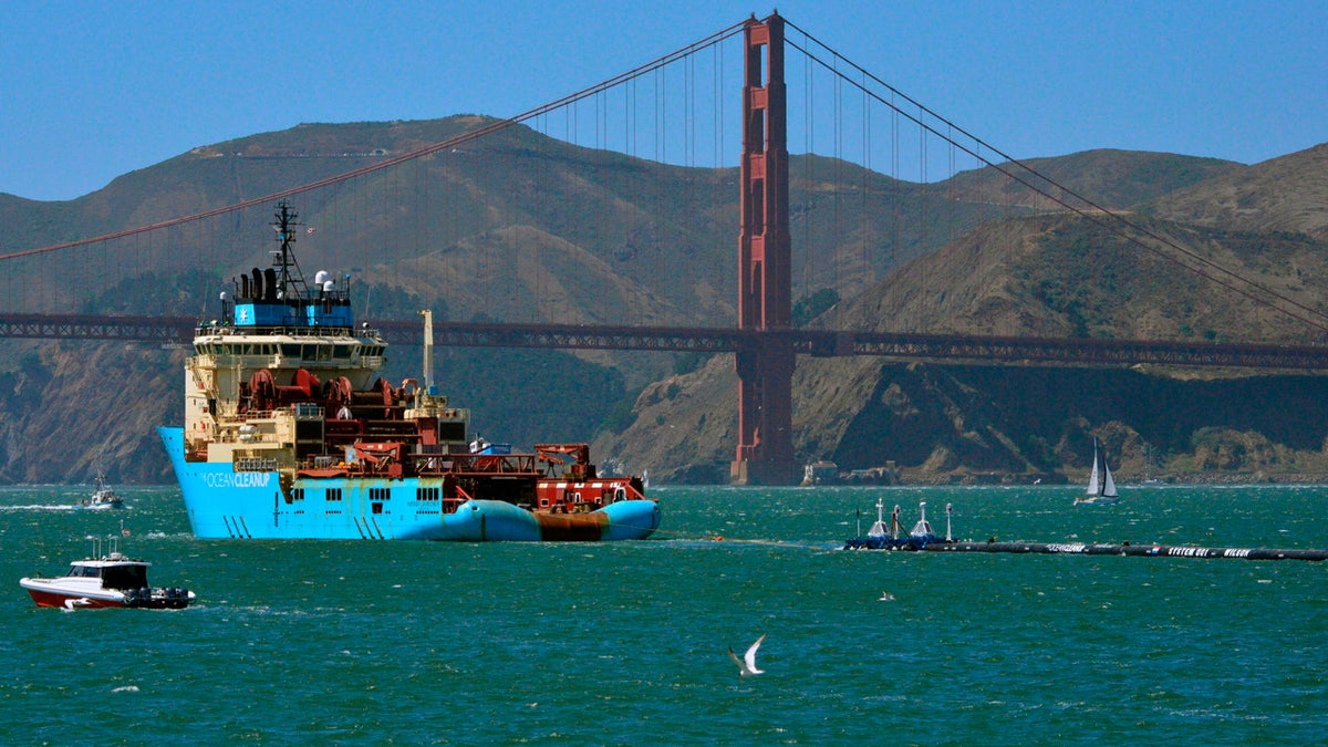 FILE- In this Sept. 8, 2018 file photo, a ship tows The Ocean Cleanup's first buoyant trash-collecting device toward the Golden Gate Bridge in San Francisco en route to the Pacific Ocean. (AP Photo/Lorin Eleni Gill, File)