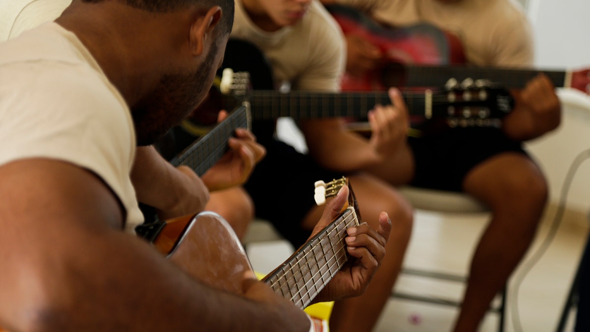 A group of young inmates play guitars during choir practice at the Las Garzas de Pacora detention center, Panama, Wednesday, Jan. 16, 2019. The group rehearsed the World Youth Day hymn at the entrance to the school. One boy played the piano, others strummed guitars and still others formed the chorus, coached by volunteers ahead of a planned performance for the pontiff. (AP Photo/Arnulfo Franco)