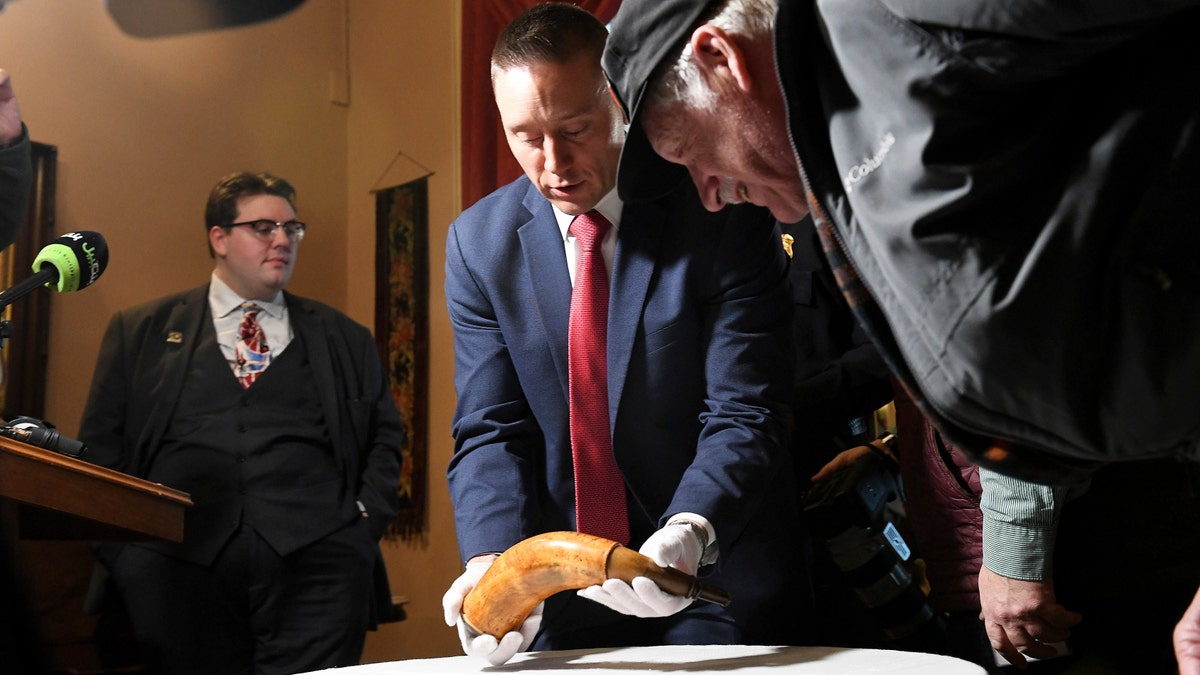 FBI special agent Jake Archer of the FBI Art Crime team holds a powder horn as John Bendzick of Dearborn, right, looks on, during a news conference, Tuesday, Jan. 15, 2019, at the Dearborn Historical Museum in Dearborn, Mich.