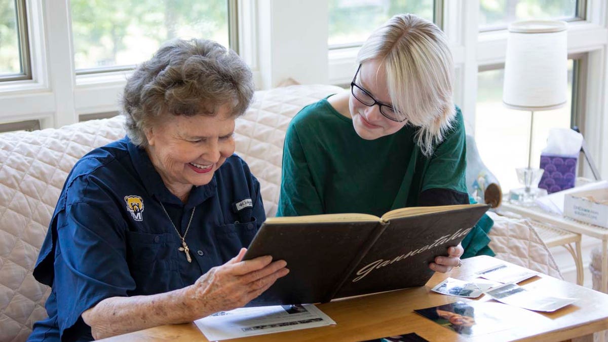 Sylvia Palmer, 84, looks at family photos with fellow Truett McConnell graduate, Baily Jarnagin, who wrote a story for the university's news spotlight.