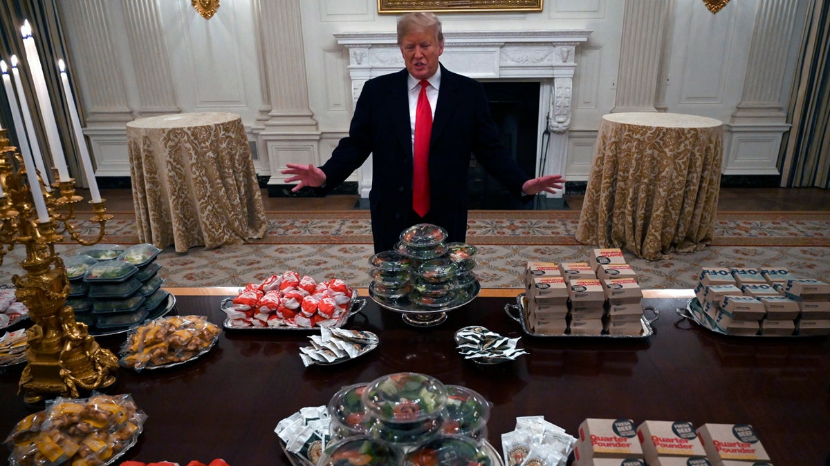 President Donald Trump talks to the media about the table full of fast food in the State Dining Room of the White House in Washington, Monday, Jan. 14, 2019, for the reception for the Clemson Tigers.