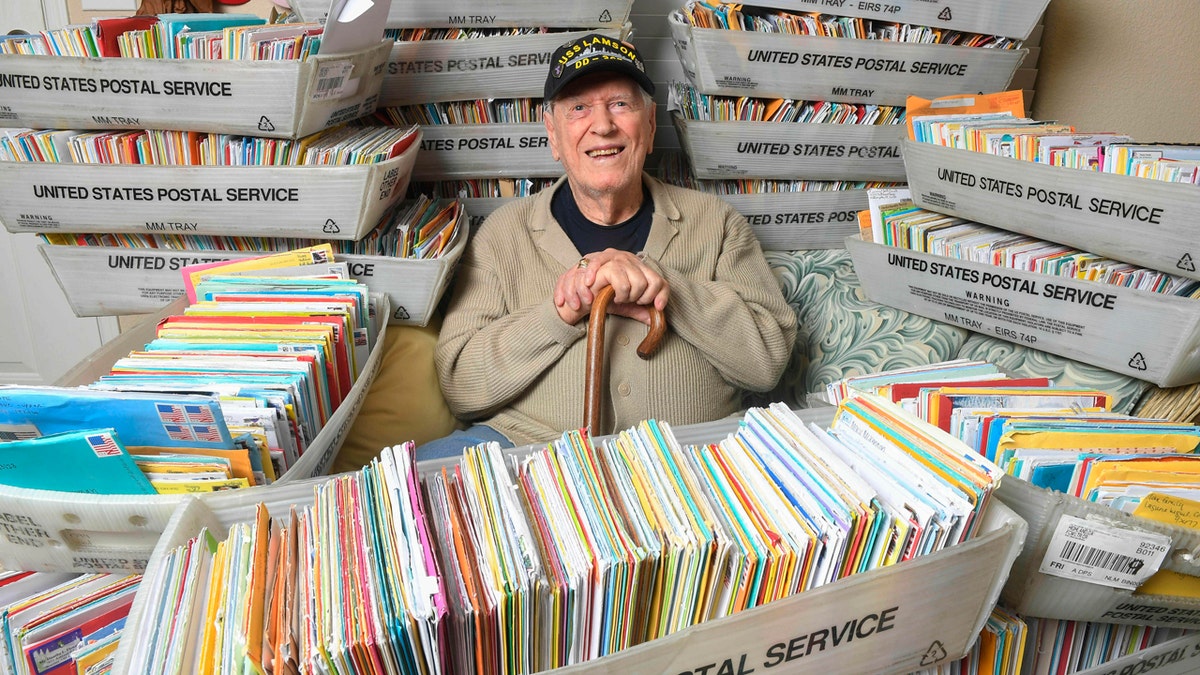 In this Tuesday, Jan. 8, 2019 photo, Duane Sherman, 96, poses at home with a small fraction of the 50,000 birthday cards he's received after his daughter's social media request for people to send him cards to cheer him up on his birthday went viral in Fullerton, Calif.