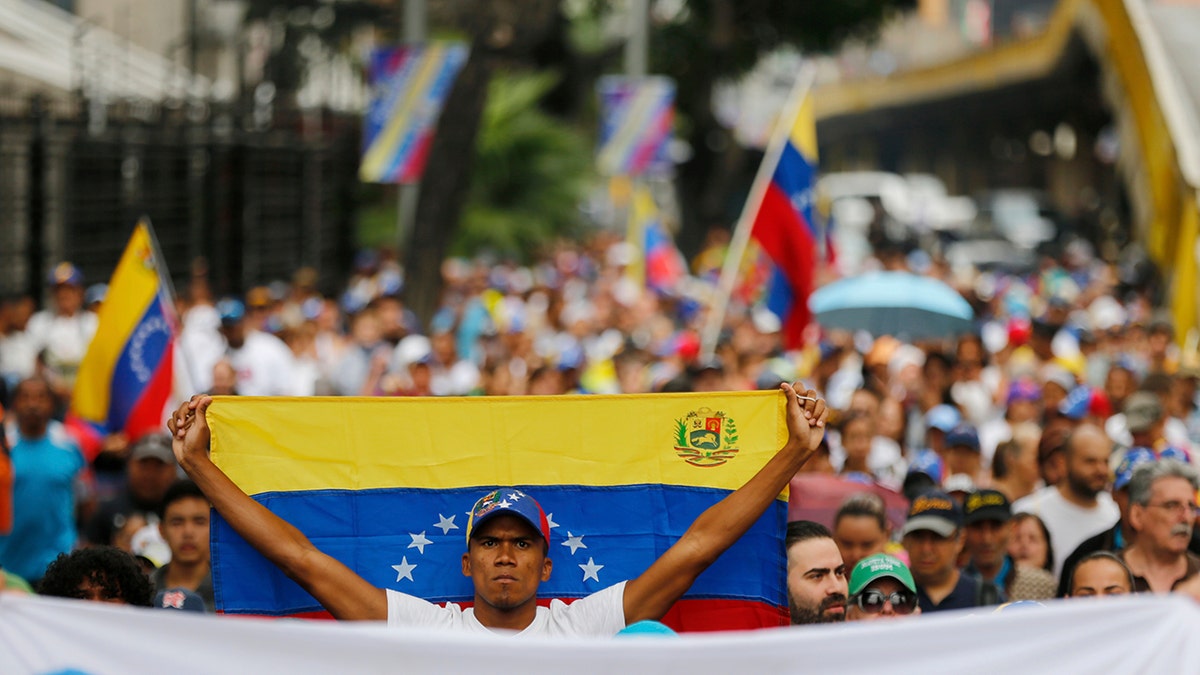 An opposition member holds a Venezuelan national flag during a protest march against President Nicolas Maduro in Caracas, Venezuela, Wednesday, Jan. 23, 2019. Venezuela's re-invigorated opposition faces a crucial test Wednesday as it seeks to fill streets nationwide with protesters in an appeal to the military and the poor to shift loyalties that until recently looked solidly behind Maduro's government. (AP Photo/Fernando Llano)