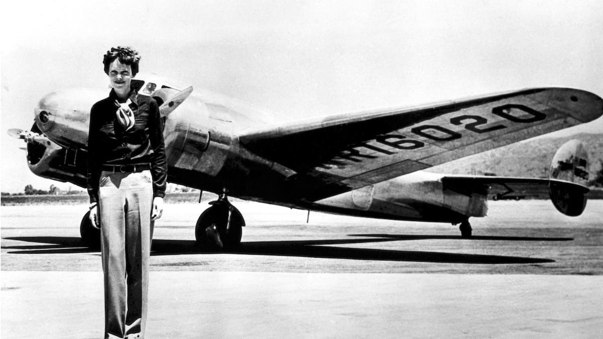 Amelia Earhart stands in front of her Lockheed Electra.