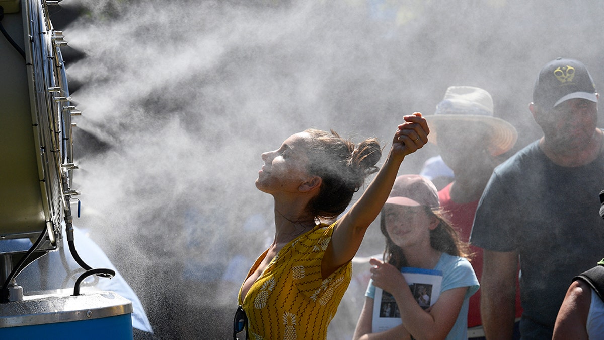 Spectators cool themselves down with a water mist fan during play on day one at the Australian Open tennis championships in Melbourne, Australia, Monday, Jan. 14, 2019.