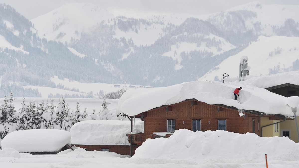 A man cleans snow from a roof on Saturday, Jan. 12, 2019 in St. Jakob, Austrian province of Tyrol.