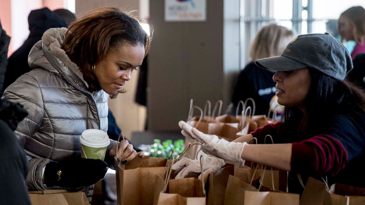 A volunteer hands out food and supplies to furloughed government workers affected by the shutdown at World Central Kitchen, the not-for-profit organization started by Chef Jose Andres, Tuesday, Jan. 22, 2019 in Washington. (AP Photo/Andrew Harnik)