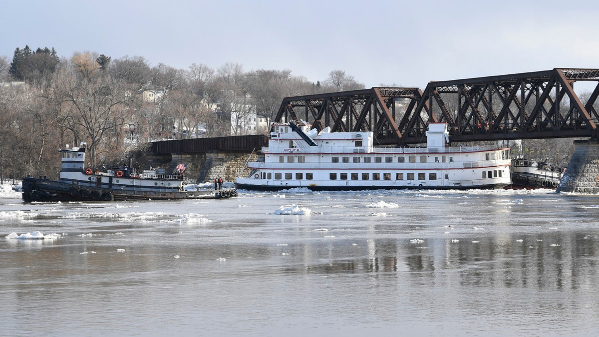 Crews from the tugboats Frances, left, and Margot work to free the Captain J.P. III cruise ship that broke away from its winter moorings in Troy, N.Y., and floated down river.