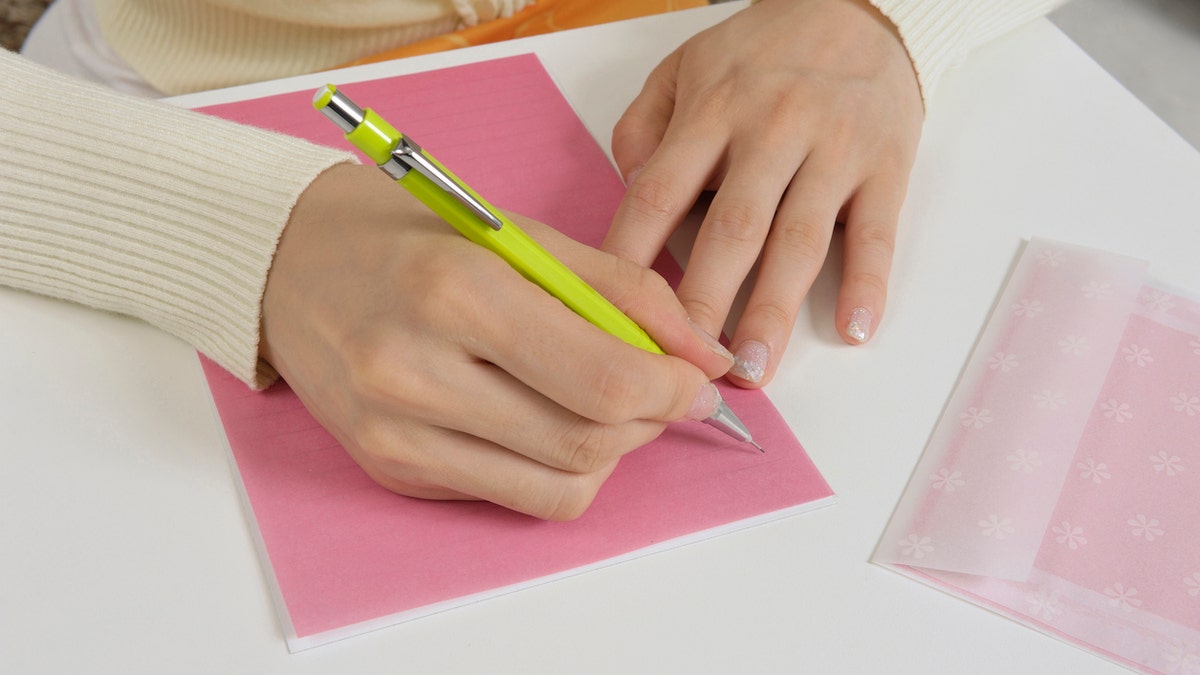 person writing a note on paper