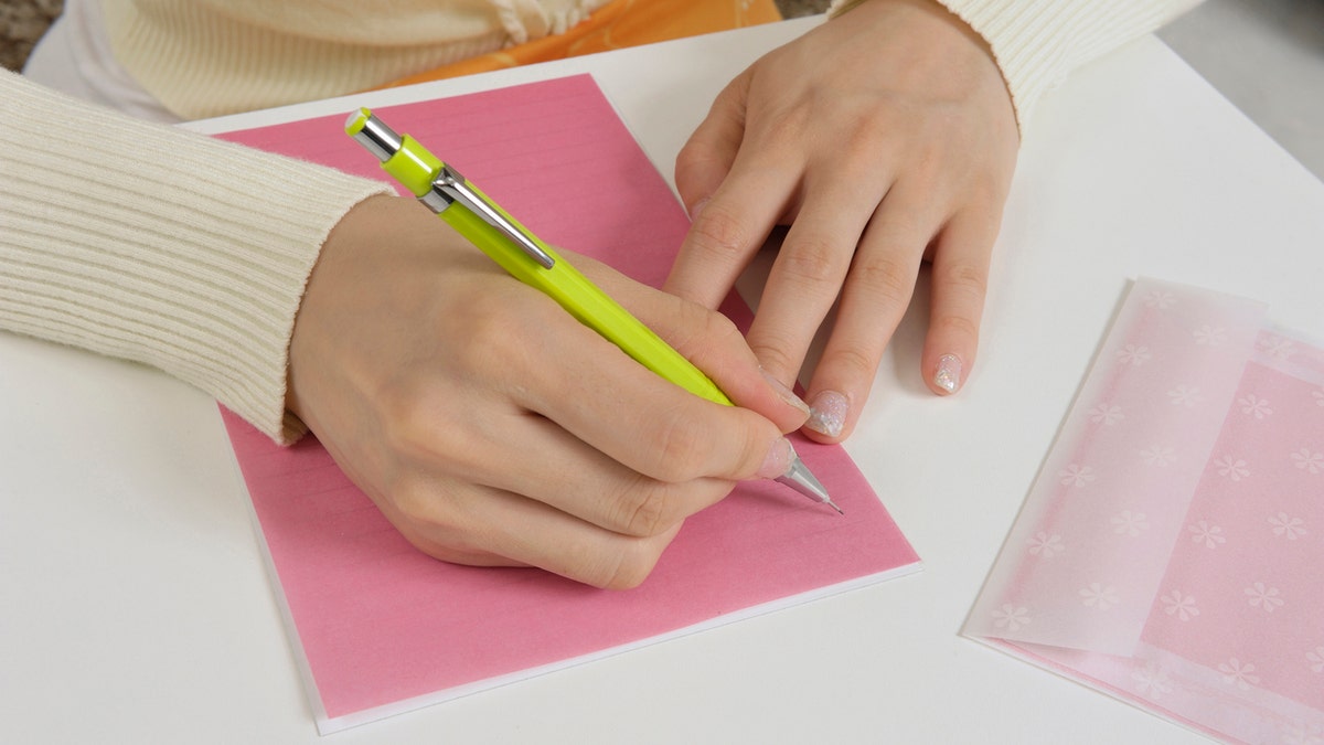 person writing a note on paper