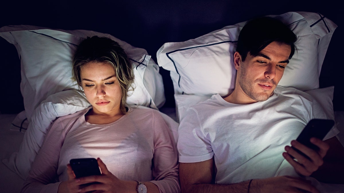 couple on phones in bed
