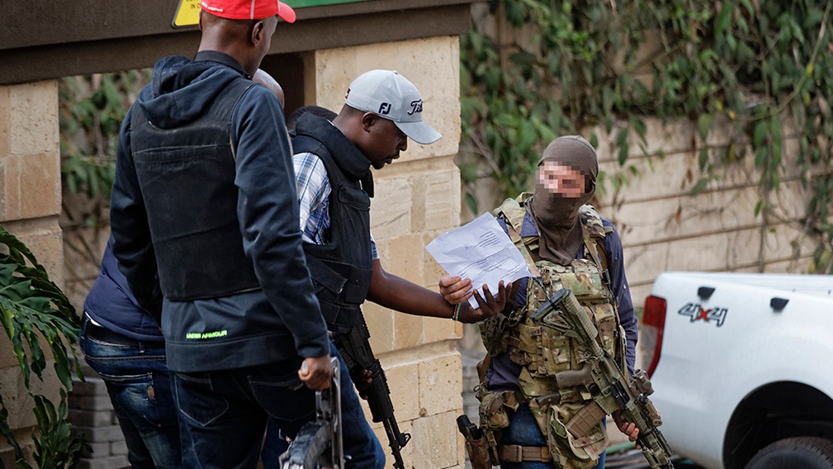 An unidentified member of Britain's SAS discusses with Kenyan security forces before entering to clear a building at a hotel complex in Nairobi, Kenya Tuesday, Jan. 15, 2019. 