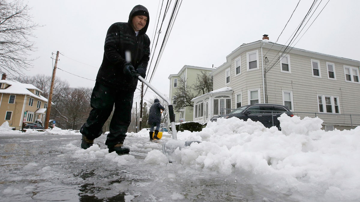 Jose De Jesus, of Norwood, Mass., shovels snow and slush in front of his home, Sunday, Jan. 20, 2019, in Norwood.